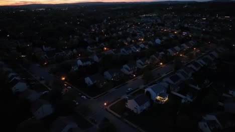 aerial establishing shot of american housing area at night in summer. golden sunset horizon. lighting lantern on street with two-story one family homes. wide shot. pa,us.