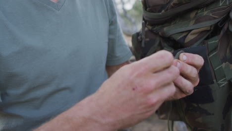 hands of caucasian male survivalist untying paracord at camp in wilderness