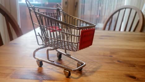 mini empty shopping trolley online home delivery concept on kitchen table pull back