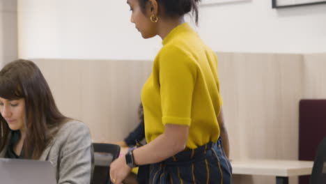 woman handing post it note to colleague