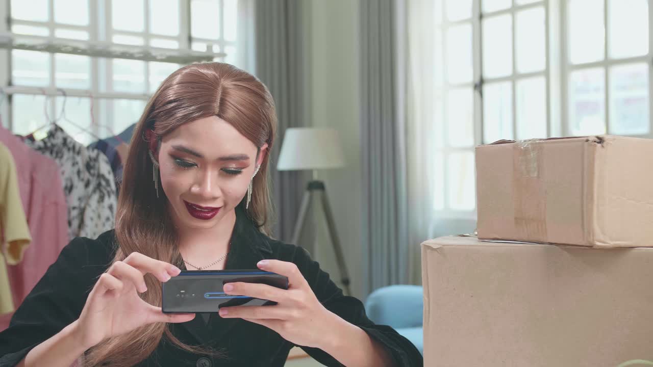 Young Asian Transgender Woman Business Owner With Boxes On The Table Happy Online Sales Job, Get An Order From Customers, Take Photos Of Product For Send To Customers
