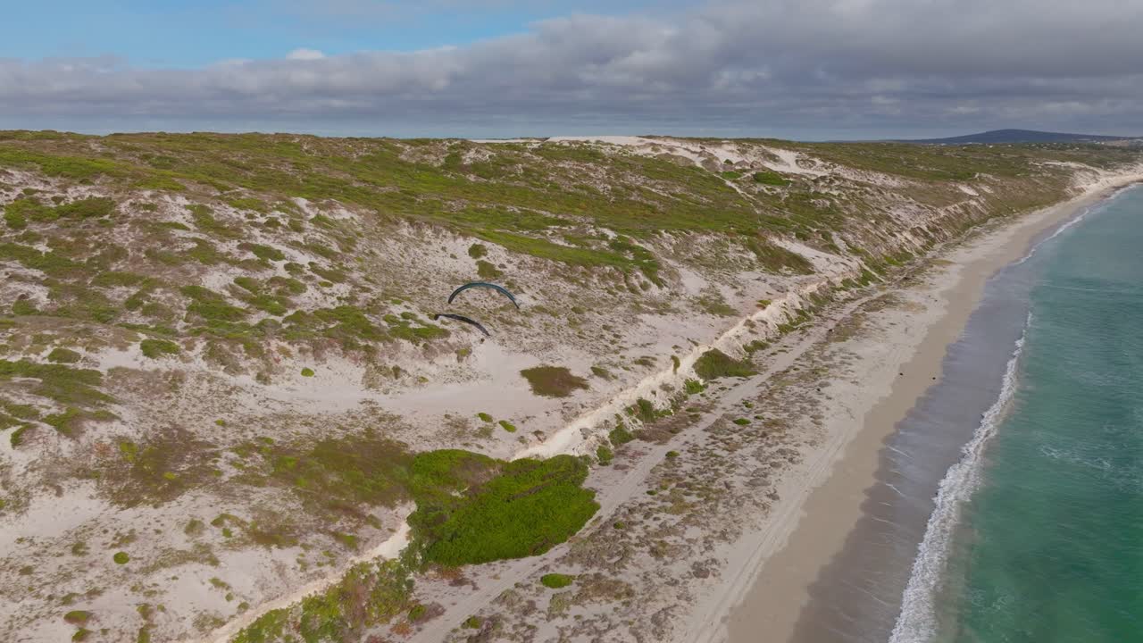 Paraglider soars above the sandy dunes and beach of Langebaan, Western Cape, South Africa