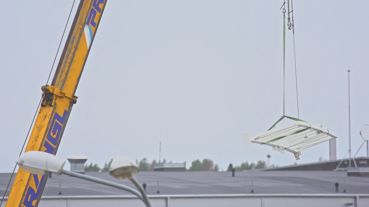 노란색 건설 크레인이 천천히 강철 막대기로 움직이고 있습니다.