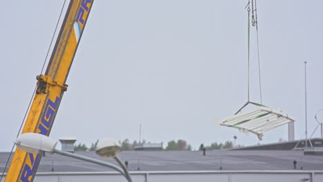 grúa de construcción amarilla moviéndose lentamente con barras de acero
