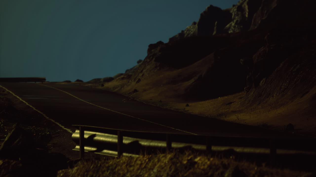 Nighttime road against a dramatic landscape under a clear sky