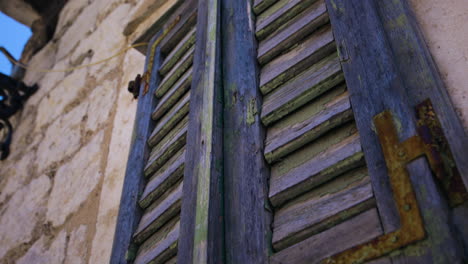 Descending-the-exterior-of-an-ancient-brick-building-with-blue-wooden-shutters