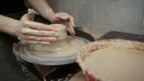 a potter teaches a woman to make clay dishes. a man takes a woman's hands