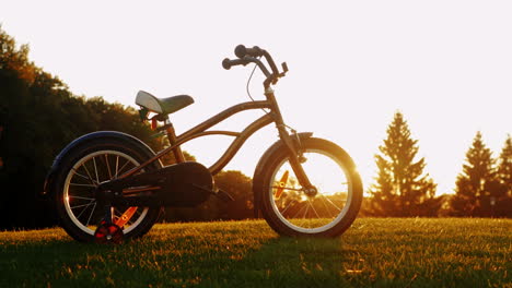 Kinderfahrrad-Auf-Grünem-Gras-Bei-Sonnenuntergang-Konzept---Nostalgie-Kindheitsträume