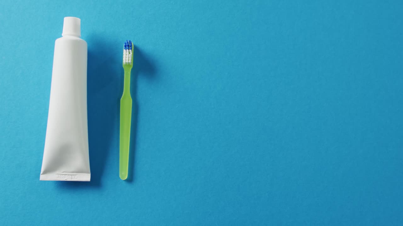 Video of close up of toothbrush and paste on blue background