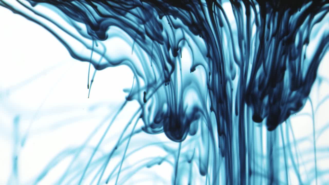 Colorful chemical liquids mix and swirl in water, forming smooth abstract patterns and organic shapes