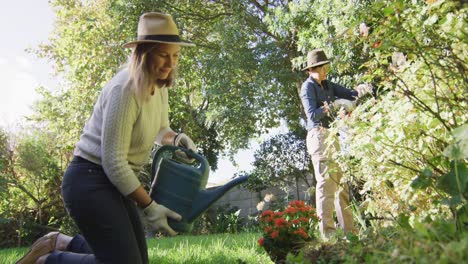 Caucasian-lesbian-couple-wearing-hats-gardening-together-in-the-garden