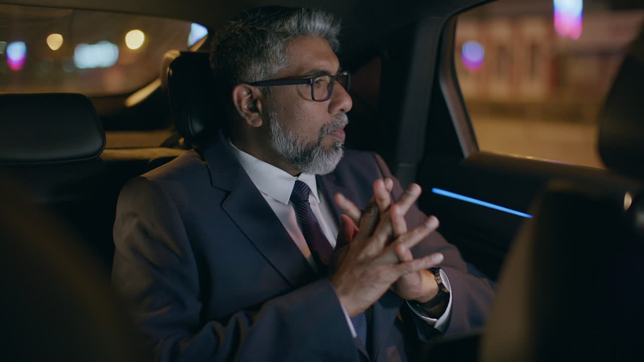 Senior Businessman Reading Laptop Screen in Car Backseat at Night