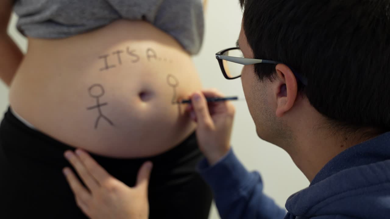 hombre pintando en el vientre de su esposa embarazada para revelar gemelos