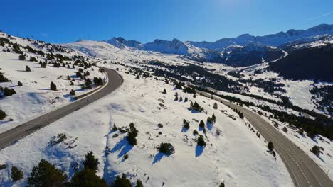 aerial drone view of a scenic road running through a snow covered mountain landscape