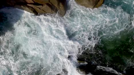 slow motion aerial descending waves breaking on rocks closing in