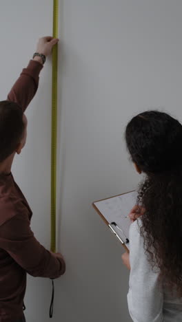 couple measuring wall for home improvement project