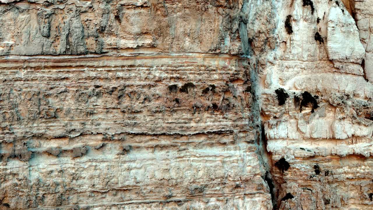 Sun drenched vertical limestone cliff textures in Gozo Malta showcasing ancient sedimentary layers and deep geological fissures under a bright summer sky captured from a dramatic low angle view