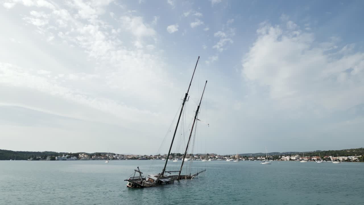 Antico relitto in una baia greca e piccole barche a vela in un tranquillo porto turistico mediterraneo.