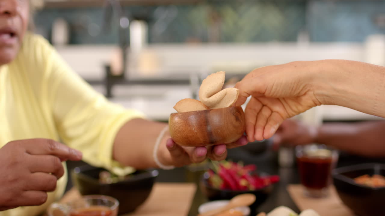 Sharing bowl of fortune cookies, friends enjoying snacks together in kitchen