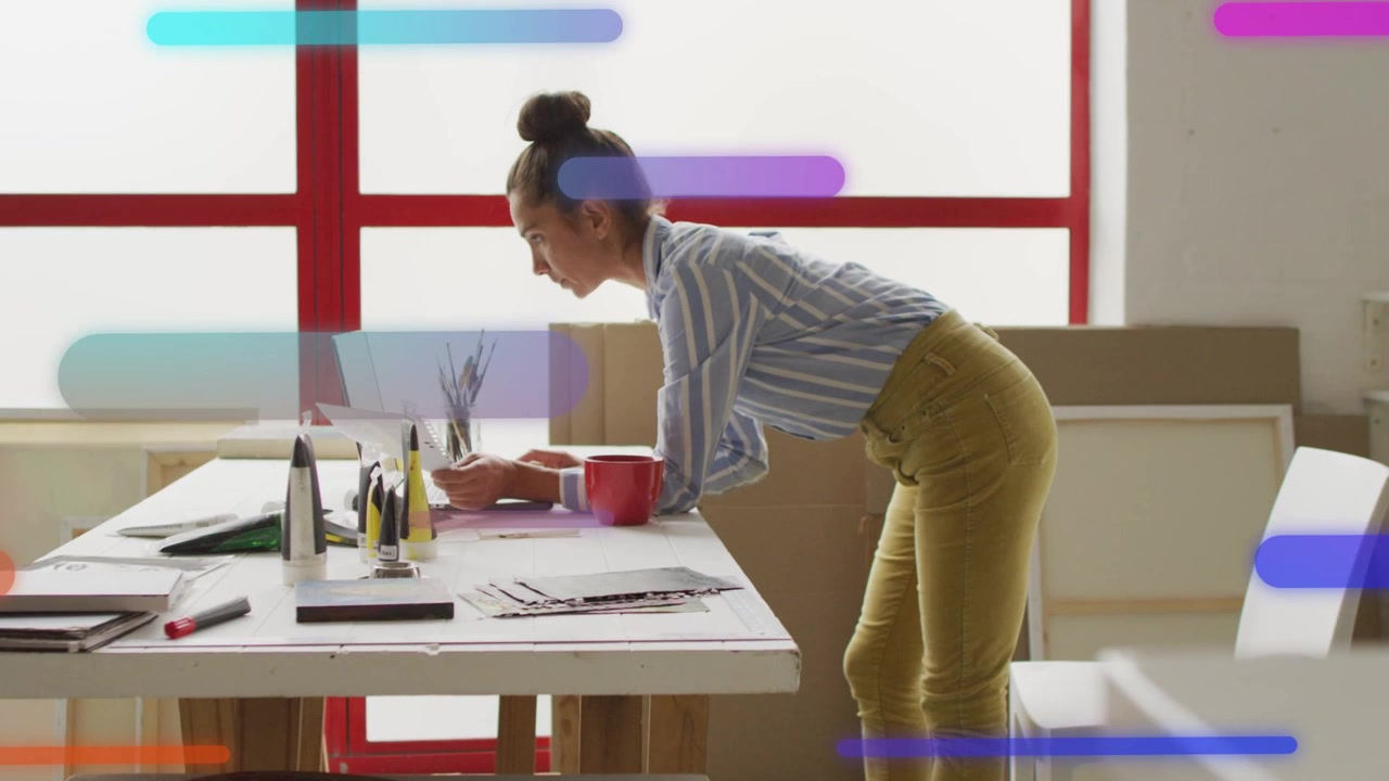 Designer chinato sul laptop, che digita e fa scorrere barre al neon sullo schermo per rivedere i layout