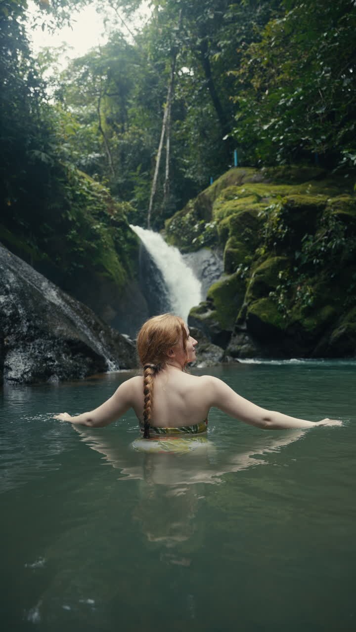 Woman Swimming in Waterfall Pool