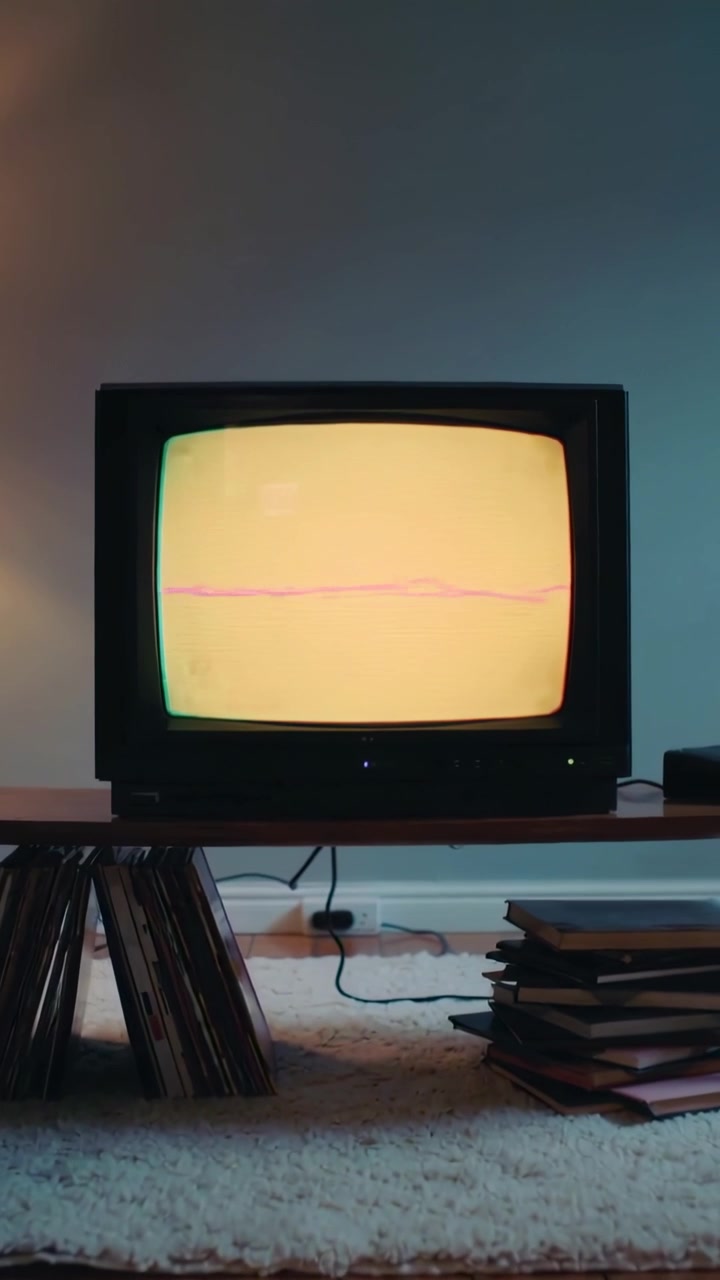 Video verticale: TV CRT che mostra un glitch del segnale, formando linee di scansione rosa su una panca a casa.