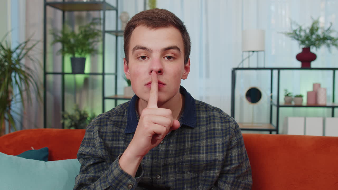 젊은 남자는 입술에 손가락을  ⁇ 러 침 ⁇ 을 유지합니다. 침 ⁇ 의 표시입니다. 소문은 말하지 않습니다. 비밀, 집에서 조용합니다.
