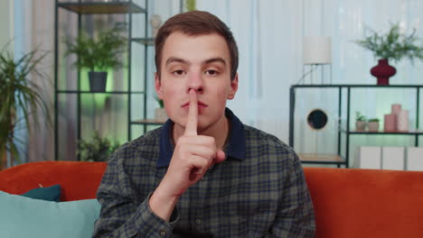 el joven presiona el dedo a los labios hace silencio signo de silencio no dice chismes secreto, tranquilo en casa