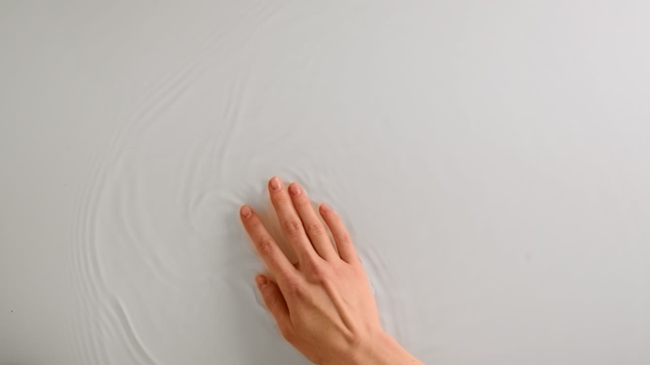 여성의 손이 물 표면을 부드럽게 만지며, 팔을 움직이면 물이 흐르고, 위쪽, 복사 공간.