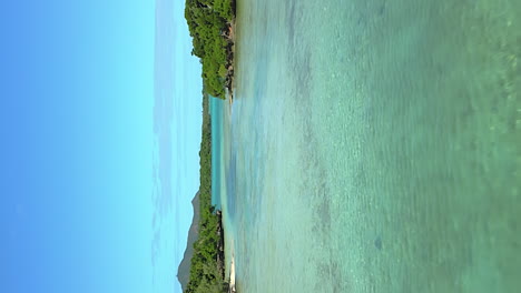 Vertical-flight-over-shallow-channel-on-Isle-of-Pines,-towards-Pacific-Ocean