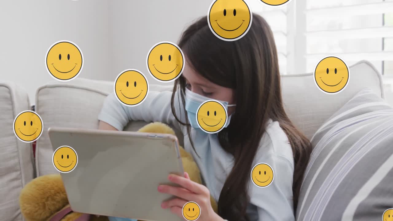 Animation of digital emoji icons over caucasian girl in face mask using tablet at home