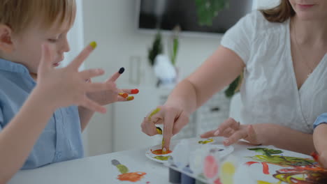 close-up children draw their fingers on paper using paints