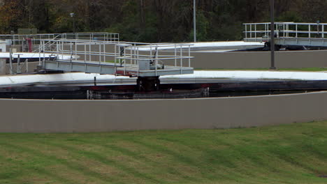 wide view of clarifier basins at a wastewater treatment plant, settling and treating processed sewage water in a structured, industrial system - panning from left to right