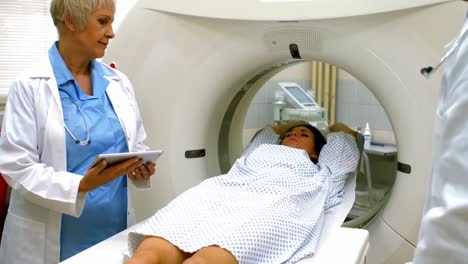 el médico revisando el cuadro de la paciente femenina en una tableta digital antes de la resonancia magnética