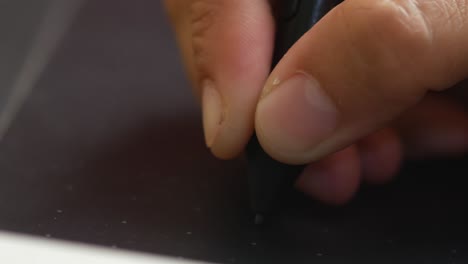 a close up illustrator's finger and hand while using a pen tablet or stylus for drawing