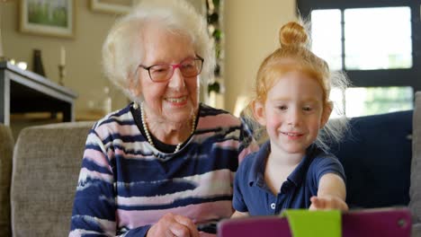 grandmother and grandson using digital tablet in living room 4k