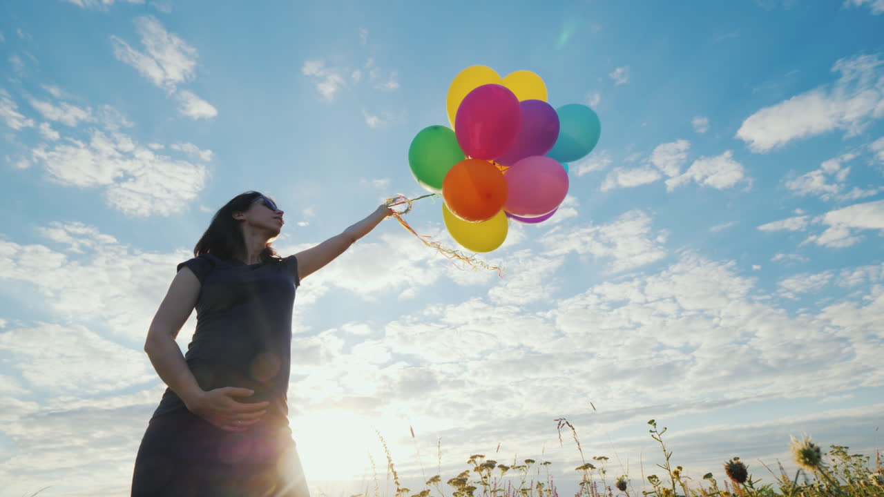 푸른 하늘을 배경으로 풍선을 가지고 노는 행복한 임산부