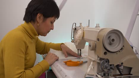 primer plano, mujer en suéter amarillo usando máquina de coser industrial