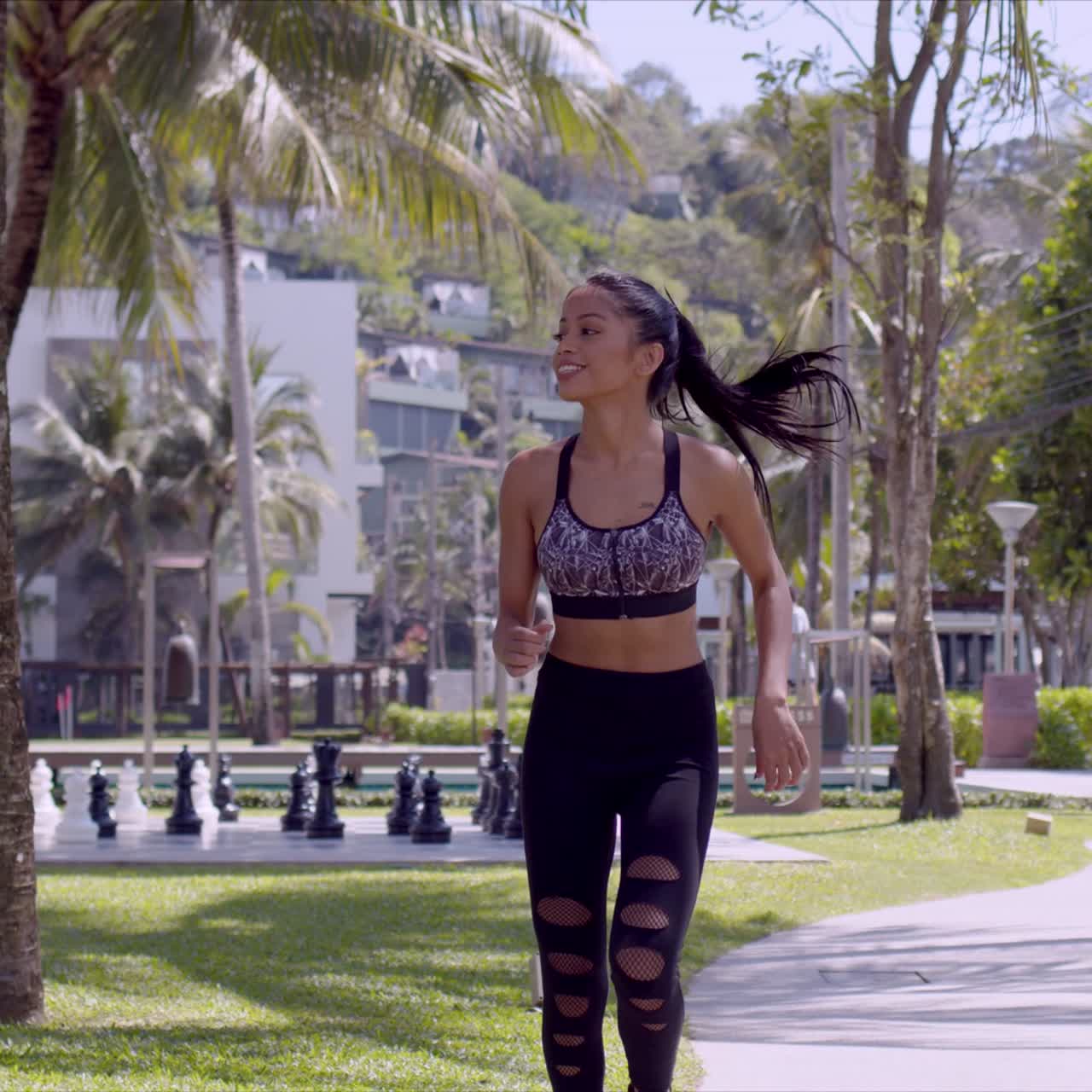 mujer alegre asiática corriendo en el parque