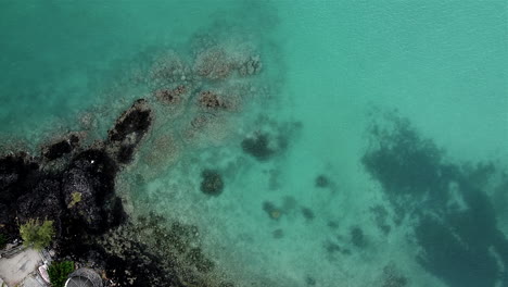 Aufsteigende-Luftaufnahme-Aus-Der-Vogelperspektive-Von-Kristallklarem-Meerwasser-Mit-Felsen-Im-Paradies