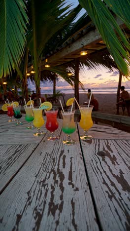 colorful cocktails on a rustic wooden table at sunset, captured from a low angle