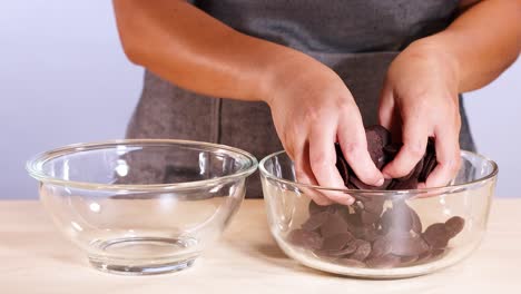 manos clasificando trozos de chocolate entre cuencos de vidrio