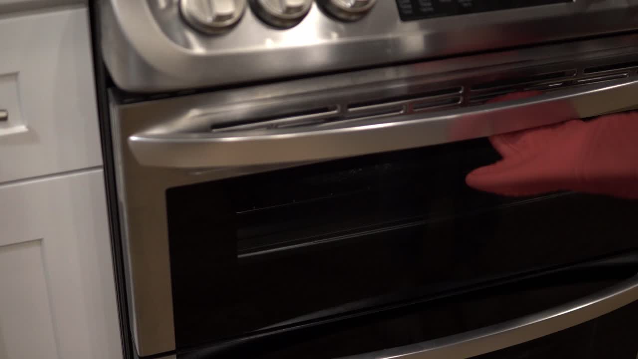 Una giovane ragazza mette una teglia nel forno con la base per preparare i biscotti shortbread milionari.