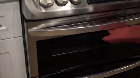 A-young-girl-puts-a-baking-pan-into-the-oven-with-crust-for-making-millionaire-shortbread-cookies