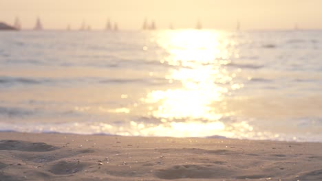 las olas y la arena se iluminan doradas por la puesta de sol, a cámara lenta