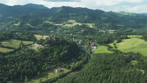 a lush green valley with scattered houses and distant mountain range, aerial view