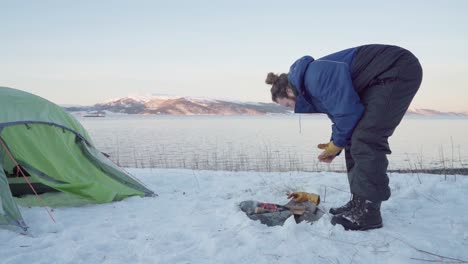 Man-Take-Off-Wet-Gloves-Then-Put-On-Rock-Around-The-Campfire-To-Dry-It