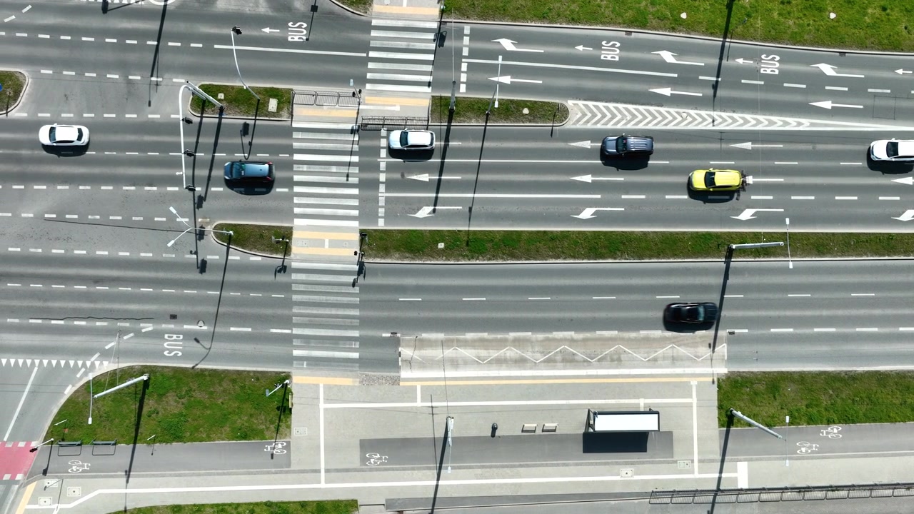 Cinematic birds eye view of a multilane city highway with cars, bus lanes, and pedestrian crossings in Gdynia. High angle perspective of urban infrastructure.