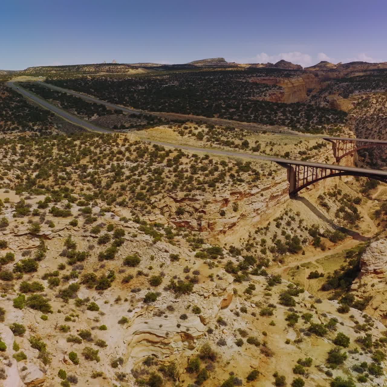 Flying close to the top of the rock in desert. Approaching two bridges connecting the edges of a huge crack in land. Utah, USA
