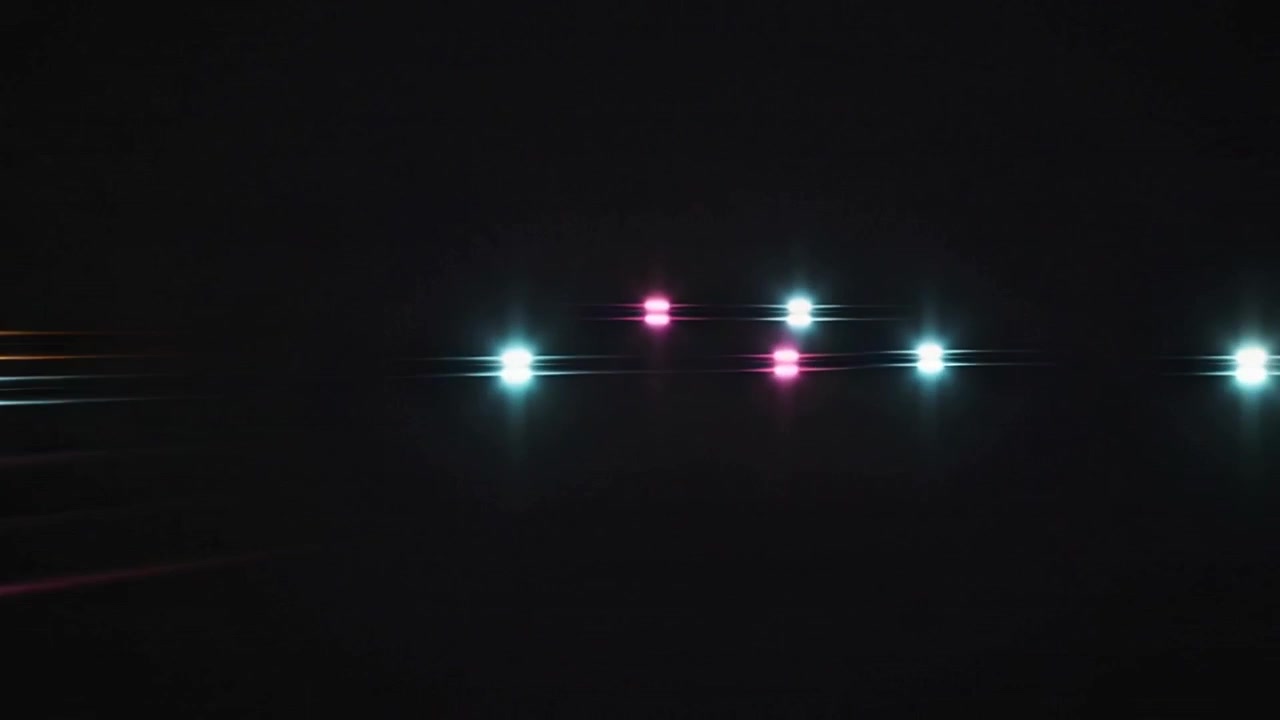 Skiftende cyan, gule og magenta farver danner lange striber hen over en natlig mark, kameraet bevæger sig